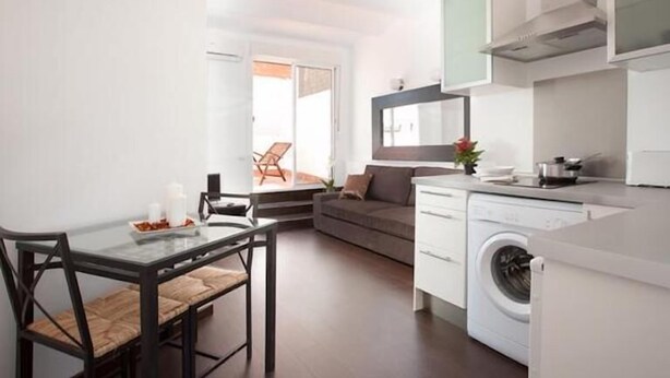 A compact kitchen with a dining area, a washing machine, and a sofa.