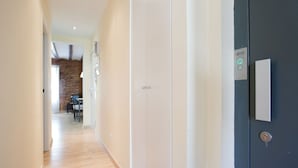 Un pasillo con suelo de madera, pared de ladrillo y una puerta con cerradura y panel de control.