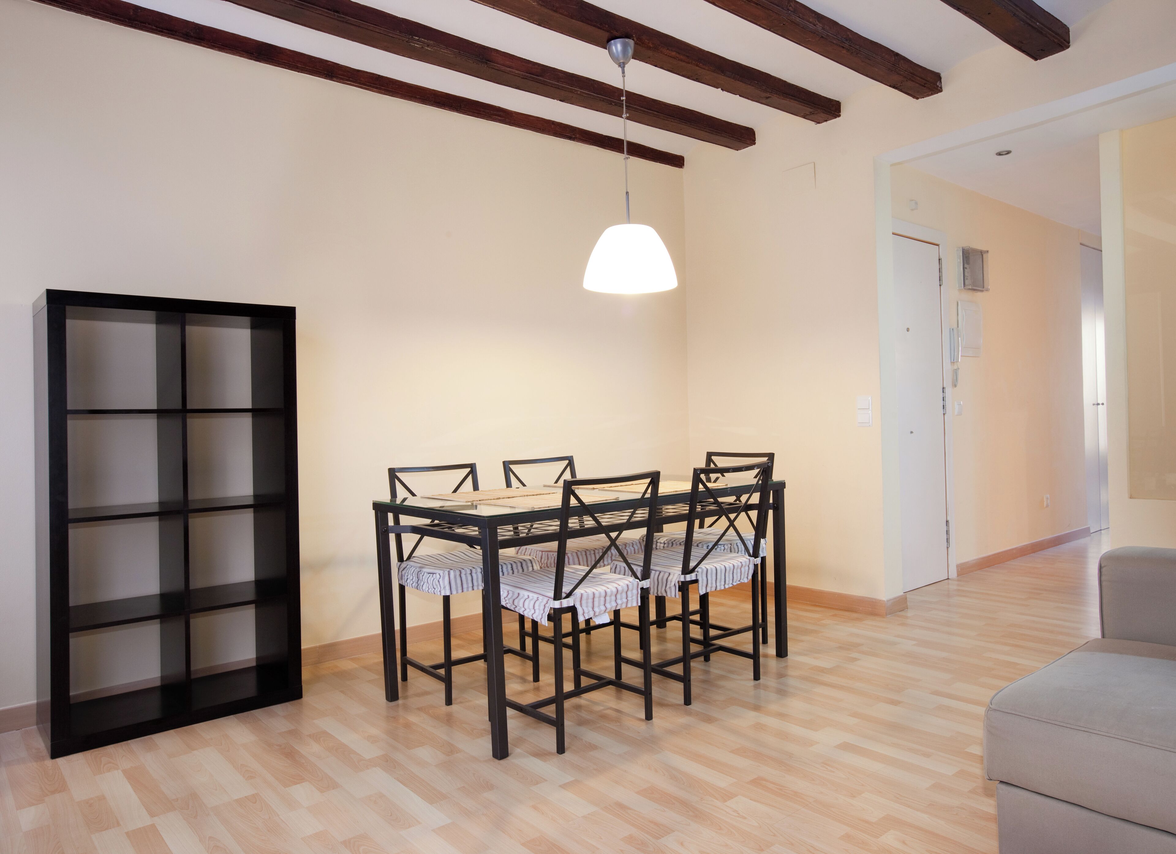 Un'area pranzo con un tavolo e sedie in legno, una lampada a sospensione e una libreria.