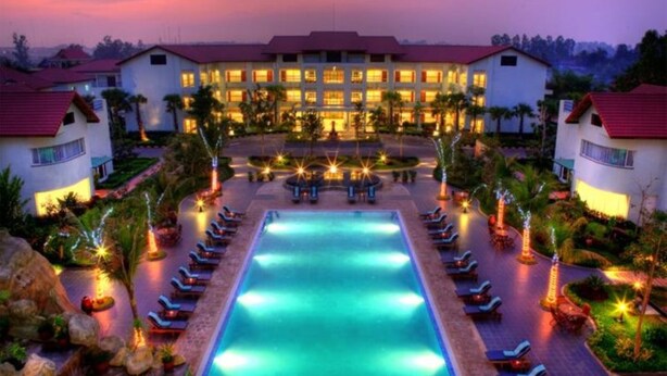 Un resort con piscina central, varias zonas de descanso y un edificio grande con múltiples ventanas.