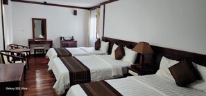 A hotel room with three beds, a desk, a chair, a mirror, a dresser, and a lamp. - EG Paradise Angkor Villa Hotel (Siem Reap)