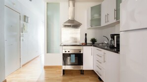 Une cuisine moderne avec des armoires blanches, une hotte de cuisinière en acier inoxydable et un four encastré.
