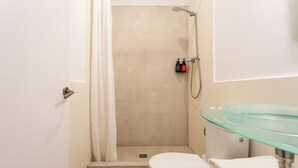 Une salle de bain avec douche, toilettes et un lavabo en verre.