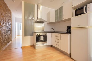 Una cocina moderna con electrodomésticos de acero inoxidable, muebles blancos y una pared de ladrillo decorativa.