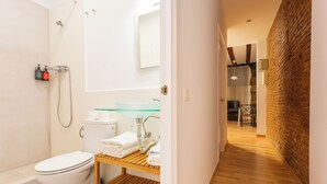 A modern bathroom with a toilet, shower, and glass sink. - Apartment near Ramblas for families or friends (Barcelona)