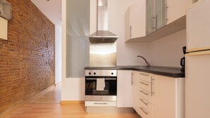 A kitchen with a brick wall, stainless steel oven, white cabinets, and a black countertop. - Apartment near Ramblas for families or friends (Barcelona)