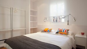 Quarto com cama, guarda-roupa, mesa de cabeceira e janela.