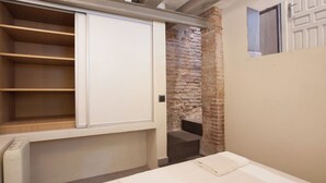 Quarto com cama, guarda-roupa embutido e parede de tijolos.