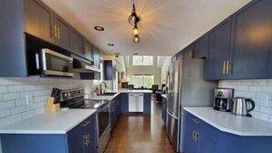 Une cuisine moderne avec des armoires bleues, des appareils en acier inoxydable et un plancher en bois.