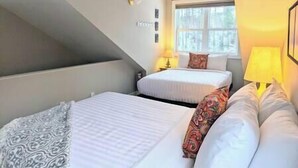 Une chambre d’hôtel avec deux lits, une fenêtre et une lampe.