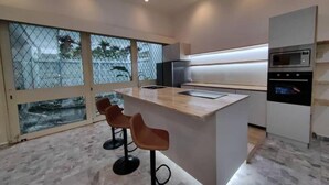 Una cocina moderna con una isla central, taburetes de bar, microondas y refrigerador.