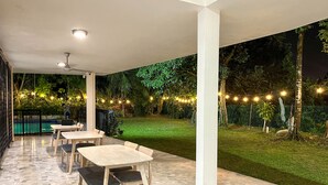 Un patio al aire libre con piscina, mesas y sillas.