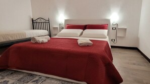 A hotel room with a bed, a smaller bed, and a bedside table with a lamp. - Delizioso Appartamento, Totalmente Ristrutturato 5 Posti Letto (Palermo)