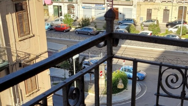A balcony with a metal railing overlooking a street with parked cars and buildings in the background. - Delizioso Appartamento, Totalmente Ristrutturato 5 Posti Letto (Palermo)