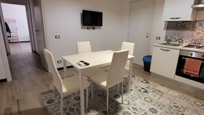 A compact kitchen with a dining table, chairs, a TV mounted on the wall, and a patterned floor. - Delizioso Appartamento, Totalmente Ristrutturato 5 Posti Letto (Palermo)