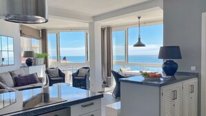 A modern kitchen with a large island, white cabinetry, and a view of the sea. - Valdecantos Marina . (Marbella)