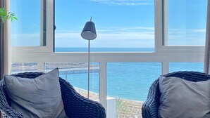 A room with a large window overlooking the sea, a floor lamp, and two wicker chairs with cushions. - Valdecantos Marina . (Marbella)