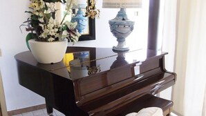 A piano with a white vase of flowers on top, a blue lamp, and a mirror on the wall. - Private Villa with hot tub, WIFI, private pool, A/C, TV, terrace, panoramic view, close to Sirmione (Polpenazze Del Garda)
