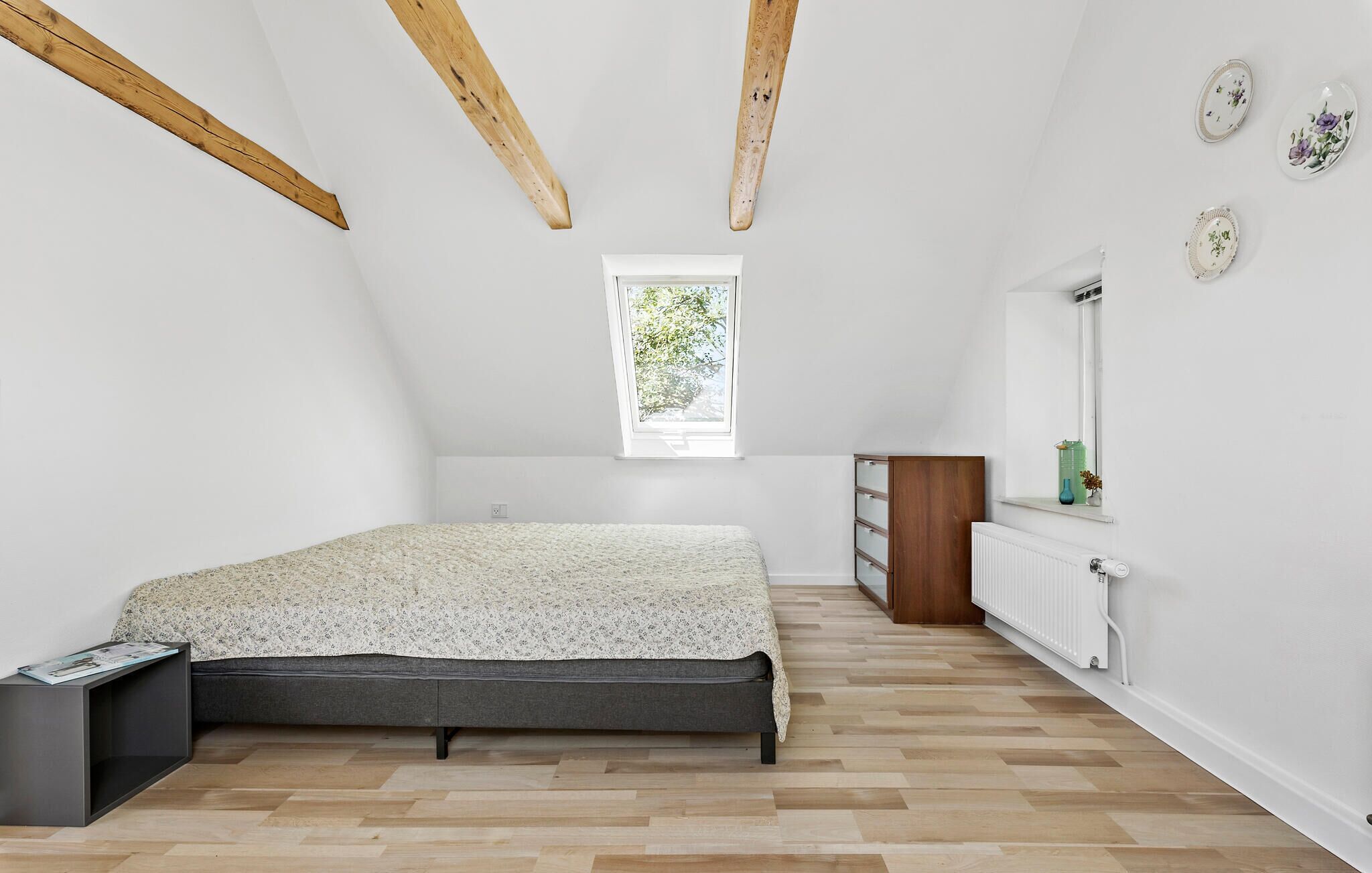 Ein Schlafzimmer mit einem Bett, einem Schminktisch, einem Fenster und einer Heizung.