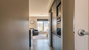 A hallway leading to a living area with a sofa and a clock on the wall.