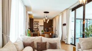 Een moderne woonkamer met een bank, een eethoek en een uitzicht door grote ramen.