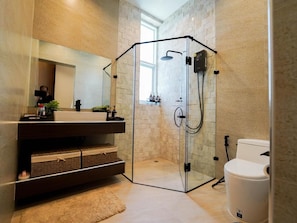 Un bany modern amb dutxa de vidre, vàter blanc i un gran mirall sobre el lavabo.