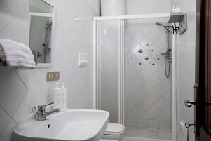 A bathroom with a white sink, a mirror, a toilet, and a glass-enclosed shower area.