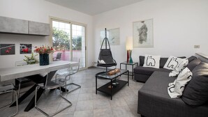Un salon moderne comprenant un canapé, une table basse en verre, un fauteuil et un coin repas avec une table et des chaises.
