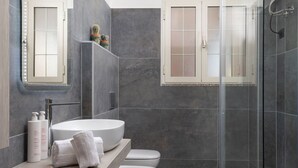 Ein modernes Badezimmer mit einem großen, weißen Waschbecken, einer Glaskabine für die Dusche und einer Toilette.