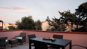 Eine Terrasse mit Korbmöbeln, einem Tisch und Stühlen sowie einem Feuer.