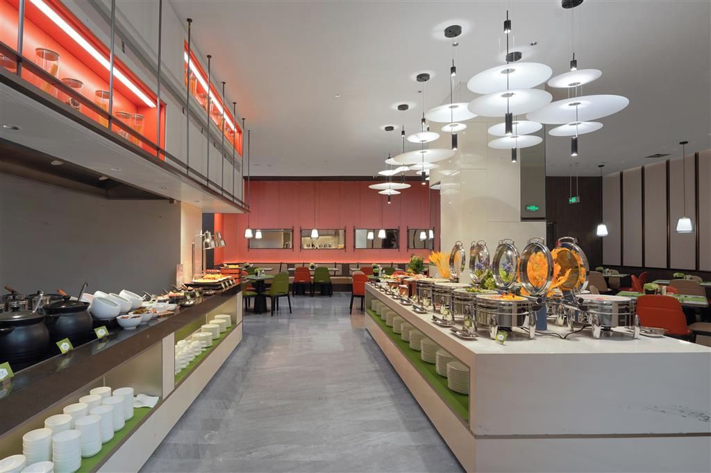 Un área de buffet con múltiples estaciones de servicio, un pasillo central e iluminación colgante moderna.