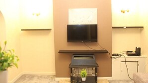 A living room with a flat-screen TV mounted above a fireplace, a small table with a plant, and a white cabinet with electronic devices. - mater dei <br>suite near royal Liverpool hospital (Liverpool)