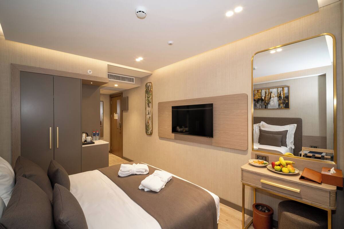 Une chambre d’hôtel moderne équipée d’un lit, d’un bureau, d’un miroir et d’une télévision.