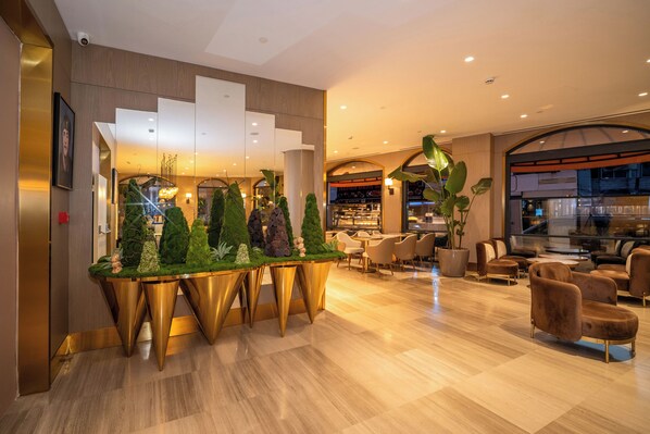 A modern lobby with a reception desk, seating area, and a staircase.