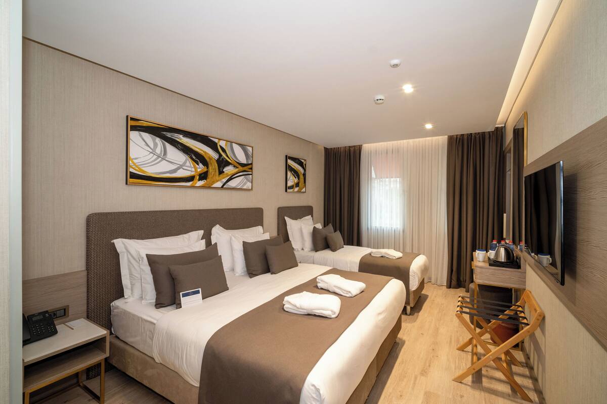 Une chambre d’hôtel avec deux lits, un bureau, une chaise et un téléviseur.
