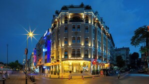 A multi-story hotel with a classic architectural design, featuring a prominent entrance with illuminated signage, a well-lit facade, and a spacious street in front. - Rayelin Hotel Old Town  (Istanbul)
