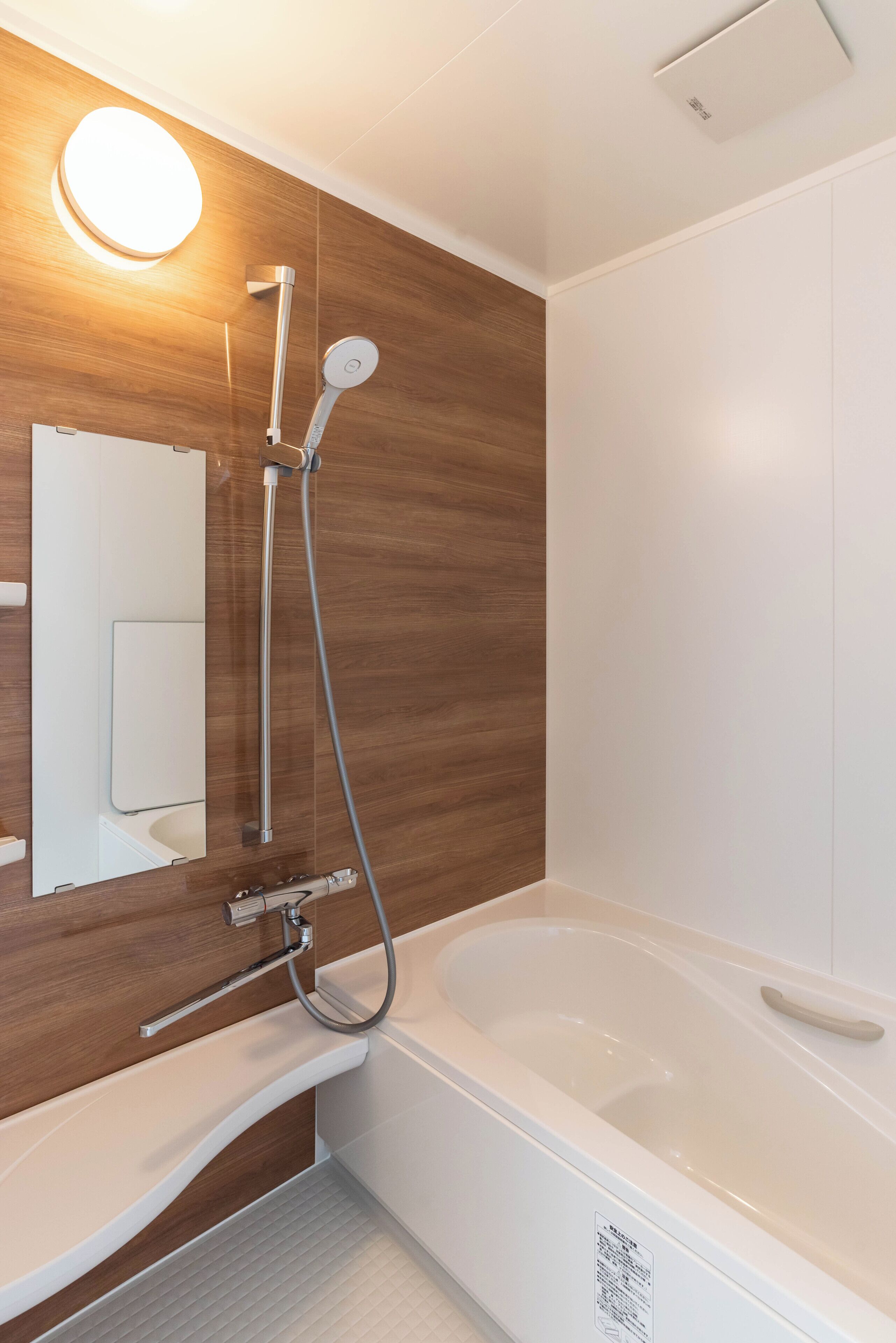 Ein modernes Badezimmer mit einer Holzwand, einer weißen Badewanne und einer Handbrause.
