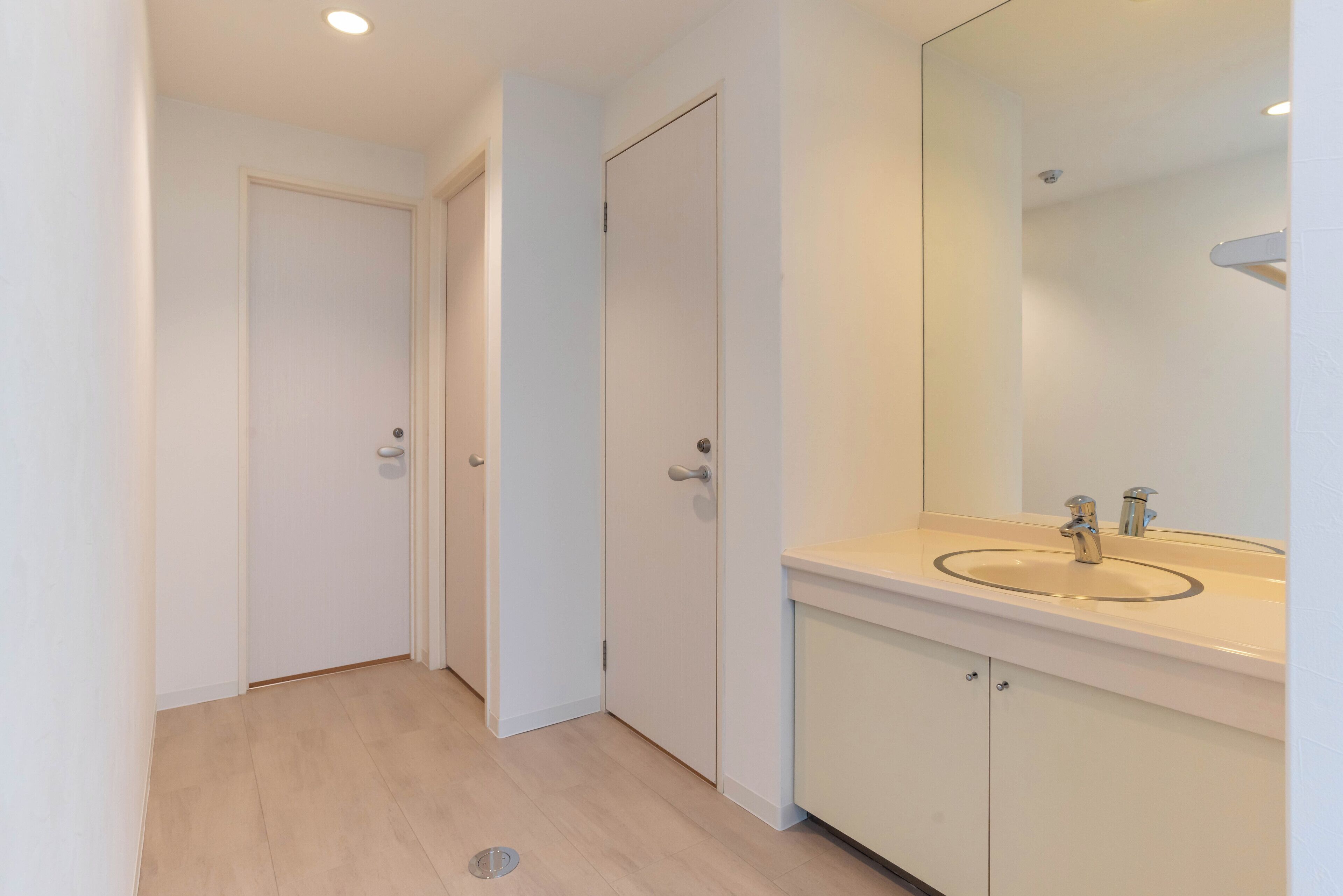 A narrow hallway with a bathroom on the right, featuring a sink and mirror.