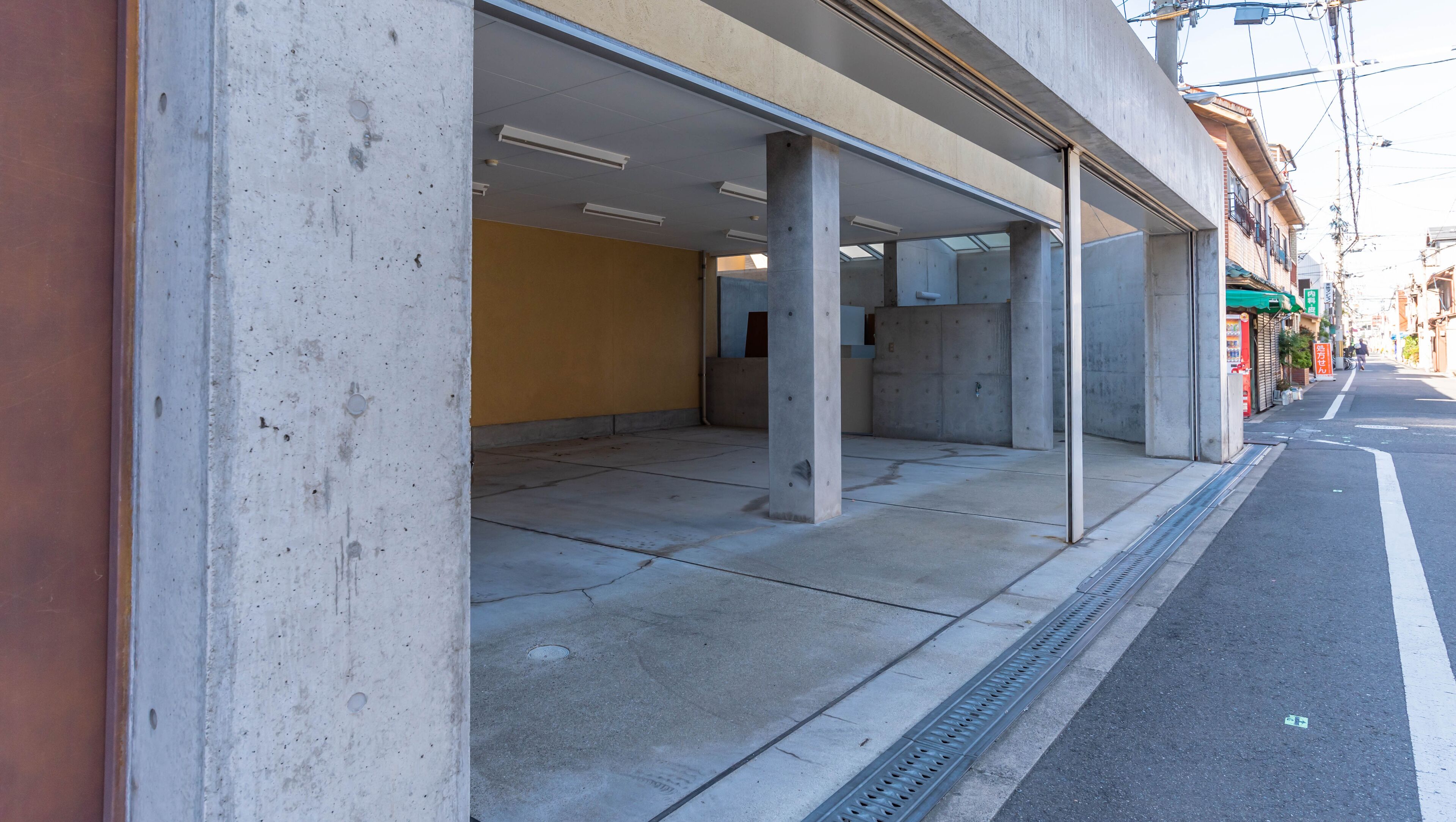 Un parking vide avec des piliers en béton et un mur jaune.