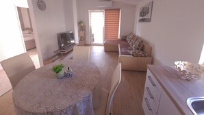 A modern living room with a round table, a sofa, and a television. - Impeccable 2-bed Apartment in Rab (Rab)