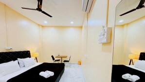 Une chambre d’hôtel équipée d’un lit, d’un bureau, de chaises et d’un ventilateur de plafond.