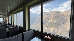 A train car with large windows offering a view of mountainous terrain. - J M S Guest House (Joshimath)
