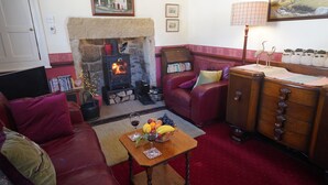A cozy living room with a stone fireplace, leather furniture, and a wooden sideboard. - Traditional 2 Bedroom Cottage in Eyam, Hope Valley (Hope Valley)