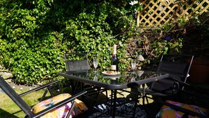 An outdoor patio with a glass table, two chairs, and a bottle of champagne. - Traditional 2 Bedroom Cottage in Eyam, Hope Valley (Hope Valley)