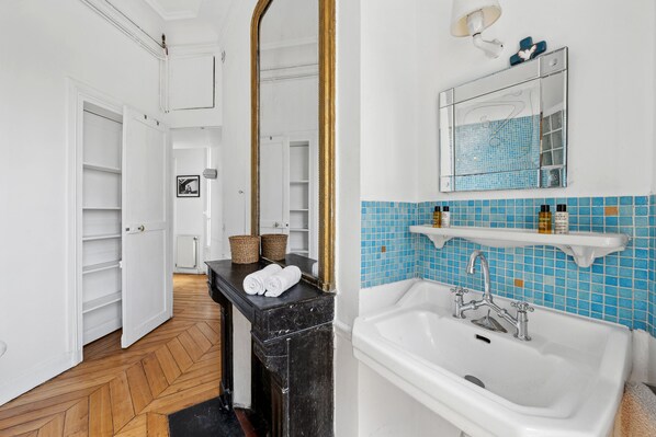Ein Badezimmer mit einem weißen Waschbecken, blau gefliesten Wänden und einem Spiegel über dem Waschbecken.