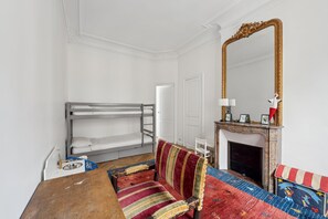 A room with bunk beds, a sofa, a fireplace, and a large mirror. - Subtly Vintage, by Veeve (Paris)