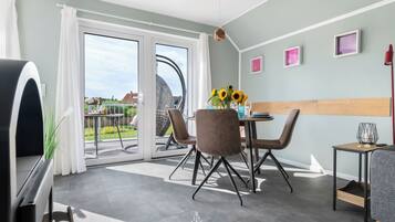 Una sala de estar moderna con comedor, amplios ventanales correderos a un balcón y vistas al exterior.
