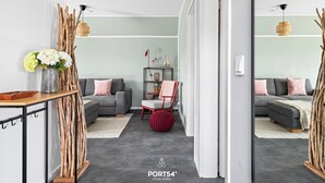 Una sala de estar moderna con un sofá gris, un sillón rojo y una mesita con un jarrón de flores.