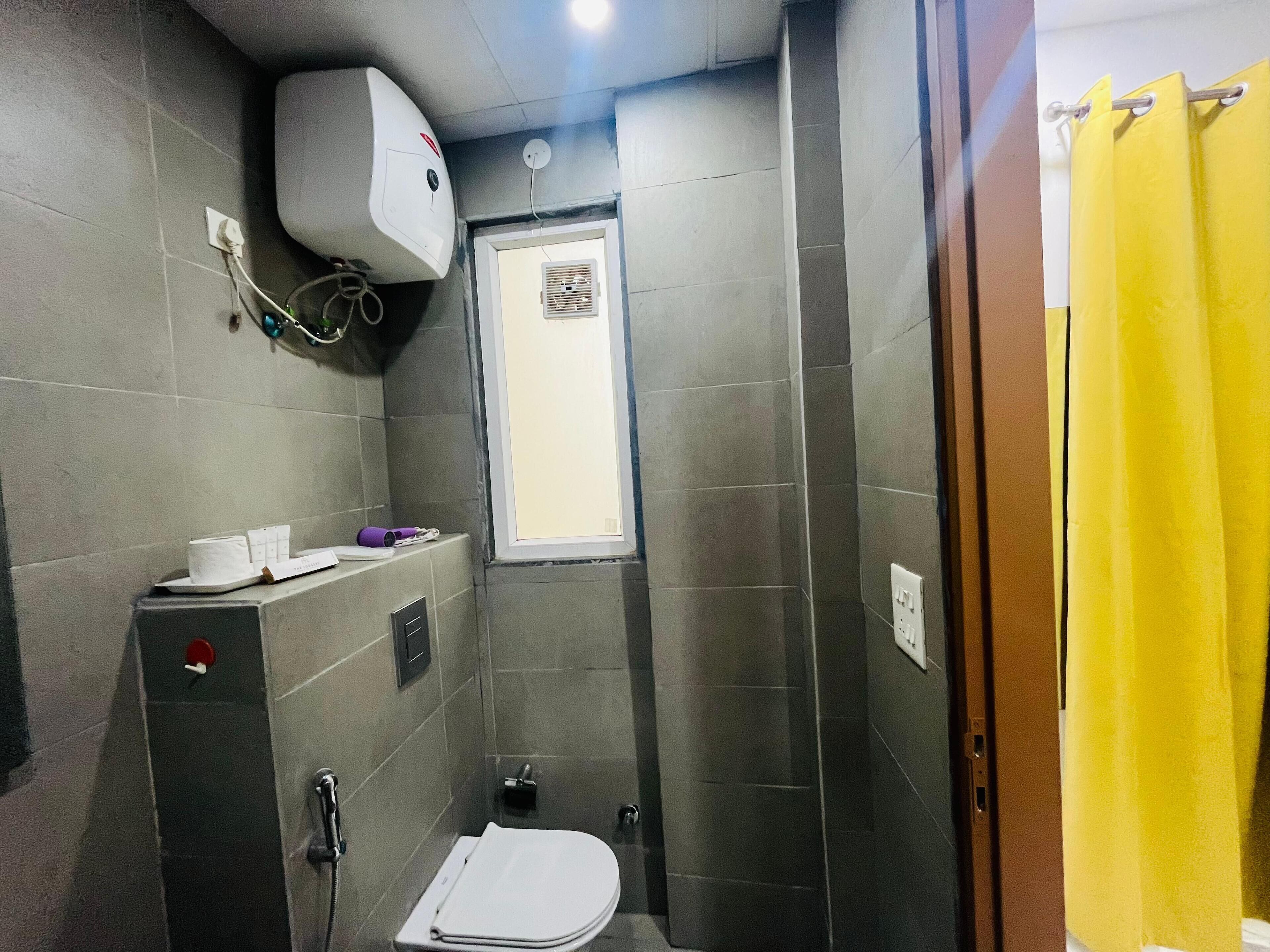 A small, compact bathroom with a toilet, a shower, and a window.