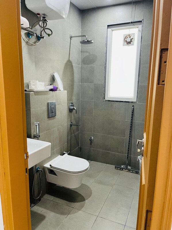 A modern bathroom with a toilet, sink, and shower. - The Lodgers Studio Apartment Sector 52 (Gurugram)